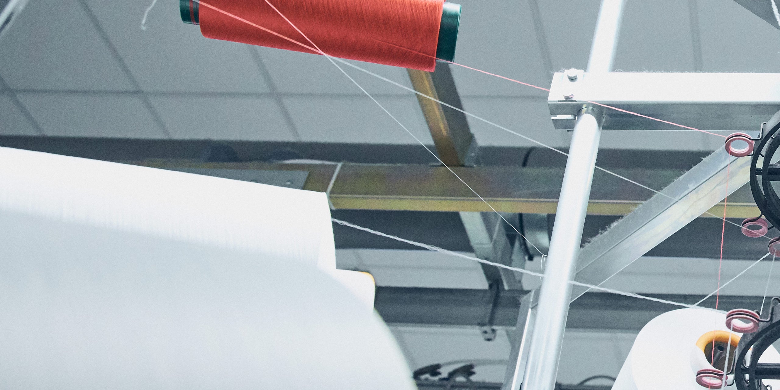 White threads from left to right with red yarn in the background.