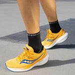 Legs of a woman running on the road wearing orange shoes and dark grey ankle high socks. 