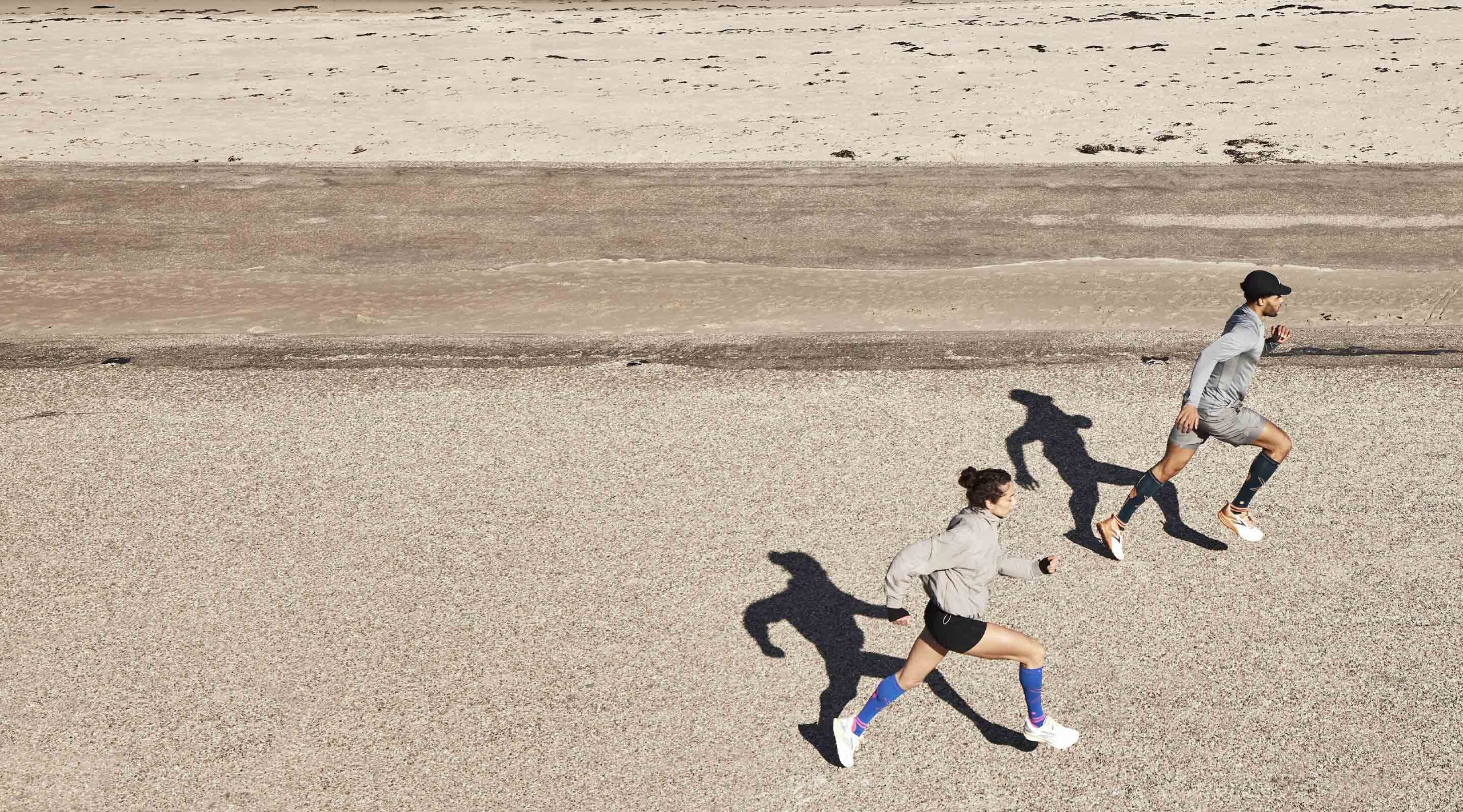 Two people running with their shadows behind them.